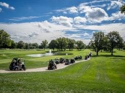 A group of people driving golf carts across a golfing field.